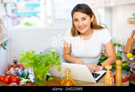 Junge Frau Kochen Salat Rezept aus dem Internet Stockfoto