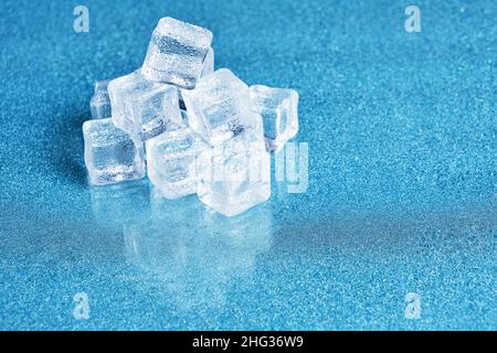 Eiswürfel sind mit Wassertropfen auf blauem Hintergrund bedeckt Stockfoto