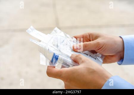 Nahaufnahme eines asiatischen Mannes hält das Coronavirus-Testkit auf dem Außenfeld in der Hand. Stockfoto