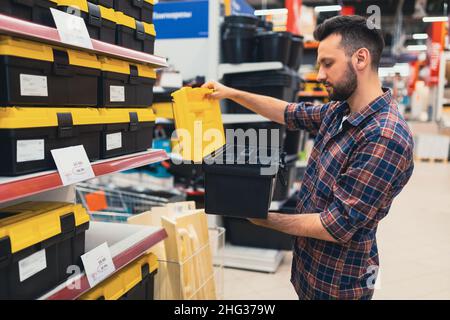 Ein Mann in einem Baumarkt wählt einen Fall für ein Werkzeug Stockfoto