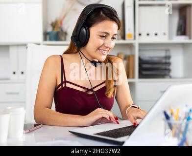 Junge Callcenter-Telefonistin mit Kopfhörern im Büro Stockfoto