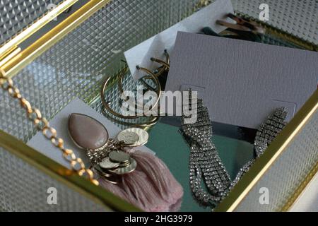 Goldene Ohrringe. Damenschmuck. Vintage Dekoration Hintergrund. Wunderschöne Silber- und Goldarmbänder, Halsketten und Ohrringe in Glaskisten. DRAUFSICHT Stockfoto