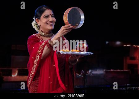 Frau, die während Karva Chauth durch ein Sieb den Mond ansah Stockfoto