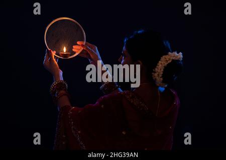Frau, die während Karva Chauth den Mond durch ein Sieb ansah Stockfoto