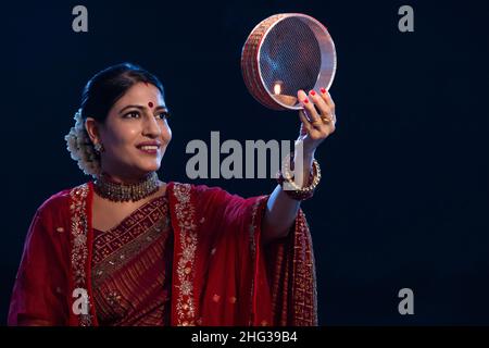 Frau, die anlässlich von Karva Chauth den Mond durch ein Sieb anschaut Stockfoto