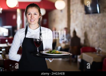 Porträt einer lächelnden jungen Kellnerin mit Serviertablett Stockfoto
