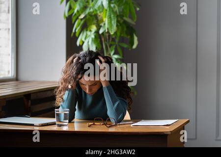 Termindruck. Frustriert gestresste weibliche Angestellte, die an Kopfschmerzen oder Bluthochdruck am Arbeitsplatz leidet Stockfoto