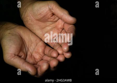 Nahaufnahme, zwei mollige Hände mit faltigen Handflächen zur Oberseite einer alten Frau auf schwarzem Hintergrund mit Kopierfläche. Oma bittet um Hilfe bei Open Stockfoto