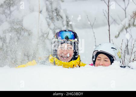 Eine fröhliche Frau und ihre Tochter verbringen gemeinsam Zeit im Snowboardpark. Mutter und Tochter der kaukasischen Ethnie in Helm und Brille Stockfoto