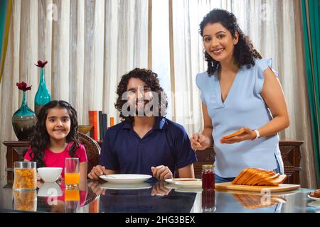 Familienmitglieder posieren zusammen vor der Kamera am Frühstückstisch Stockfoto