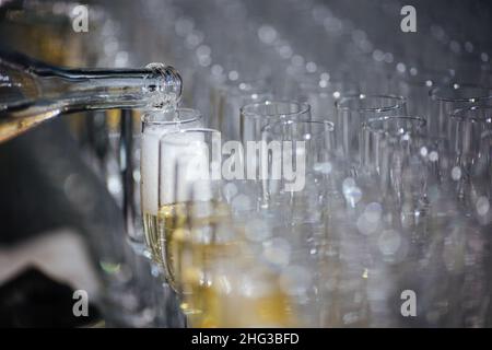 Champagner, der Gläser aus einer Flasche eingießt. Spritzer und Tropfen. Konzept für den Urlaub. Stockfoto