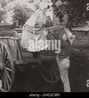 Vintage-Foto von Verliebten. „Catch Me Tom!“. USA. 1906 Frau, die kurz vor dem Sprung vom Wagen in die Arme eines Bauern steht. Stockfoto