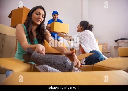 Mädchen Verpackung Blumenvase und Übergabe der Box an den Jungen zum Stapeln Stockfoto