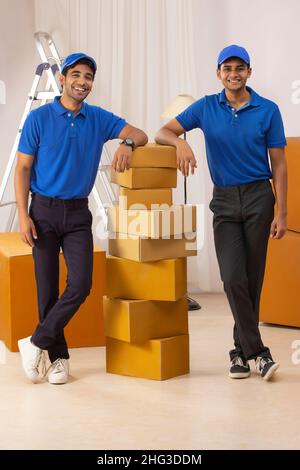 Delivery Boys in Uniform stehend mit gelehnt auf Pappkartons Stockfoto