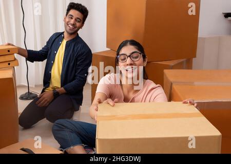 Mädchen, das Pappkarton platziert und der Junge beobachtet Stockfoto