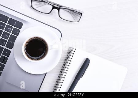 Draufsicht auf den Arbeitsbereich, Holzschreibtisch mit Laptop-Notebook, Tastaturstift, Brille, Telefon, Notebook und Tasse Kaffee. Mit einem Kopierplatz, flach Stockfoto