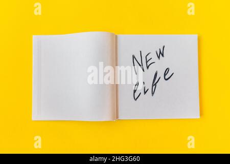Neues Leben. Notizblock mit leeren Seiten auf gelbem Hintergrund. Stockfoto