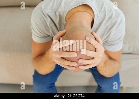 Gestresster depressiver verzweifelter Mann, der durch Probleme, seinen Kopf in den Händen zu halten, verwüstet wurde Stockfoto