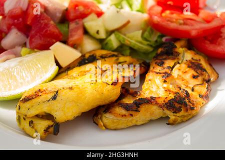Gegrilltes Hähnchenfilet mit rohem Gemüse auf einem weißen Teller Stockfoto
