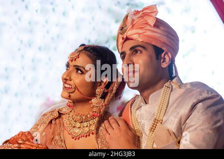 Seitenansicht der indischen Braut und Bräutigam in traditionellem Hochzeitsoutfit Stockfoto