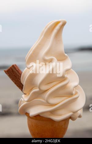 Ein Soft-Serve-Eis mit einer Schokoladenflocke, die an einem Sommertag an einem Strand in Guernsey, Channel Islands, aufgenommen wurde Stockfoto