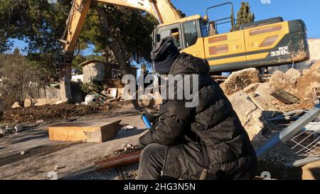 Jerusalem, Israel. 17th Januar 2022. Ein Palästinenser sitzt auf den Trümmern eines von den israelischen Behörden abgerissenen Gebäudes auf dem Gelände des Familienhauses eines Palästinensers, Salhiya, das am 17. Januar 2021 in Jerusalem, Israel, im Scheich-Jarrah-Viertel geräumt werden soll. Salhiyas Familie ist seit 2017 mit einer Räumungsdrohung konfrontiert, als das Land, in dem sich sein Haus befindet, für den Schulbau bestimmt wurde. Das palästinensische Viertel Sheikh Jarrah ist derzeit das Zentrum einer Reihe von Eigentumsstreitigkeiten zwischen Palästinensern und rechtsgerichteten jüdischen Israelis. Ein bisschen Hous Stockfoto