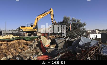 Jerusalem, Israel. 17th Januar 2022. Ein Bagger zerstört eine Struktur auf dem Gelände des Familienhauses eines Palästinensers, Salhiya, das am 17. Januar 2021 in Jerusalem, Israel, im Scheich-Jarrah-Viertel geräumt werden soll. Salhiyas Familie ist seit 2017 mit einer Räumungsdrohung konfrontiert, als das Land, in dem sich sein Haus befindet, für den Schulbau bestimmt wurde. Das palästinensische Viertel Sheikh Jarrah ist derzeit das Zentrum einer Reihe von Eigentumsstreitigkeiten zwischen Palästinensern und rechtsgerichteten jüdischen Israelis. Einige Häuser wurden nach einem Cour von israelischen Siedlern besetzt Stockfoto