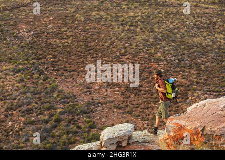 Lange Seitenansicht eines jungen kaukasischen Wanderers, der auf Felsen in der Wildnis unterwegs ist Stockfoto