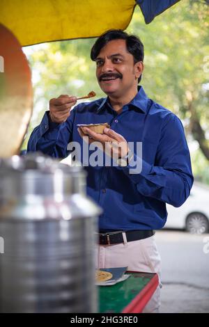 Mann mittleren Alters in Blau kurz essen Street Food Stockfoto