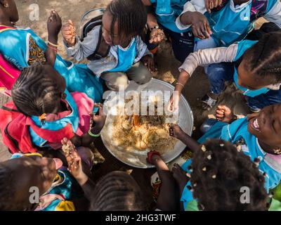 Senegal, Afrika - Jan 2019: Senegalesische Kinder essen in der Schule gemeinsam auf traditionelle Weise. Stockfoto