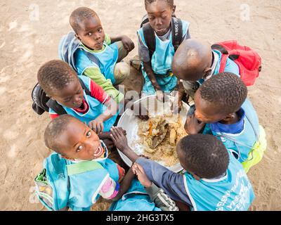 Senegal, Afrika - Jan 2019: Senegalesische Kinder essen in der Schule gemeinsam auf traditionelle Weise. Stockfoto