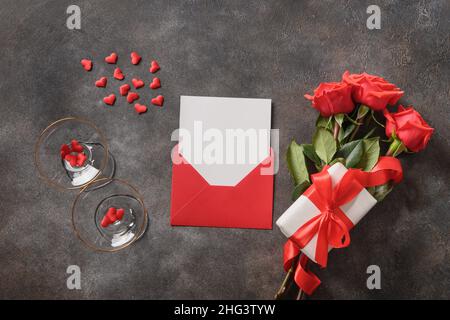 Valentinskarte mit Liebesbrief im Umschlag, roten Rosen und Weingläsern für Champagner. Blick von oben. Platz für Text - Be My Valentine. Stockfoto