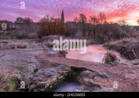 Malmesbury, Wiltshire, England. Dienstag 18th Januar 2022 - nach einem starken Frost über Nacht wird der Himmel in der Morgendämmerung rosa über Malmesbury und der alten Klappbrücke, die in Richtung der historischen Marktstadt am Hang führt. Quelle: Terry Mathews/Alamy Live News Stockfoto