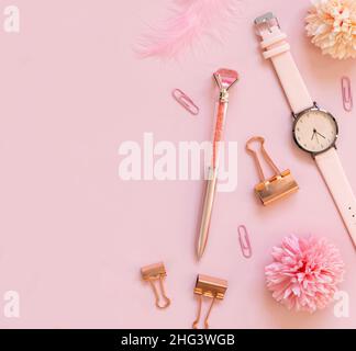 Rosa Schulzubehör und Schreibwaren auf pastellrosa Hintergrund Draufsicht, Kopierbereich. Girly Arbeitsplatz mit Uhr, Stift, Büroklammern, Blumen und feige Stockfoto