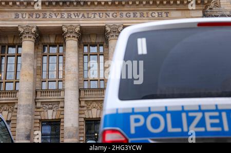 18. Januar 2022, Sachsen, Leipzig: Polizeifahrzeuge stehen vor dem Bundesverwaltungsgericht vor dem Beginn einer Berufungsverhandlung vor dem Strafsenat des BGH 5th wegen eines Mordes in einem Wettbüro. Acht Jahre nach der tödlichen Schießerei in einem Berliner Wettbüro überprüft der Bundesgerichtshof (BGH) die Urteile gegen Mitglieder einer Rocker-Gruppe. Sie stürmten angeblich 2014 in die Kneipe und schossen einen 26-jährigen Mann. Das Landgericht Berlin hatte acht Angeklagte wegen Mordes zu lebenslanger Haft und den Rocker-Führer zu lebenslanger Haft wegen Anstiftung zum Murren verurteilt Stockfoto