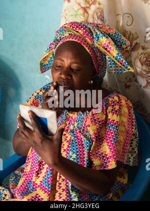 Senegal, Afrika - Januar 2019: Porträt einer schönen senegalesischen Frau in traditioneller Kleidung namens Boubou, die typisch afrikanisches Make-up macht Stockfoto
