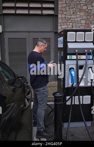 Der Fahrer zahlt, um sein Auto an einer EV-Ladestation in bristol England zu laden Stockfoto