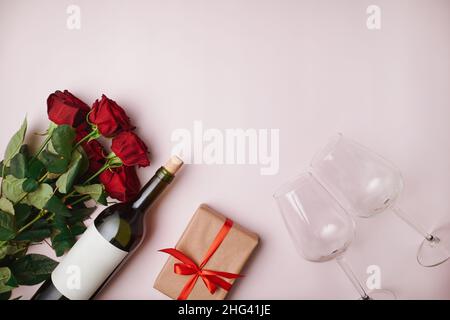 Eine Flasche Wein, ein Bouquet und Geschenke auf hellem Hintergrund. Stockfoto