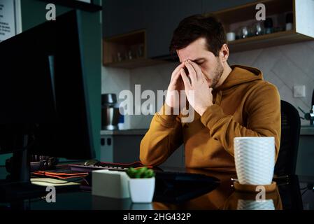 Man arbeitet spät am Heimarbeitsplatz, Remote-Work-Konzept. Burnout und emotionaler Stress aufgrund von Überlastung Stockfoto