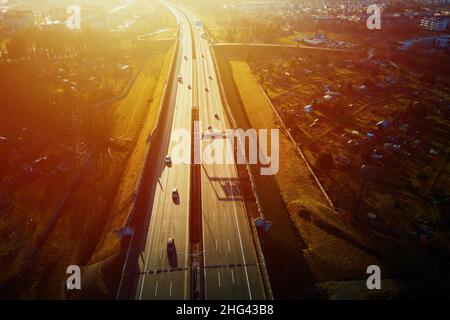 Autoverkehr auf der Autobahn bei Sonnenuntergang, Luftaufnahme. Roadtrip, Lieferung und Logistikkonzept Stockfoto