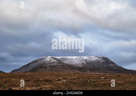 Errigal. County Donegal. Schneebedeckter Gipfel im Winter mit bewölktem Himmel und schönen Farben Stockfoto