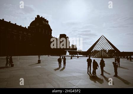 Fotografie gegen das Licht auf dem Museumsplatz des Louvre in Paris, Silhouette von Touristen und Besuchern Stockfoto