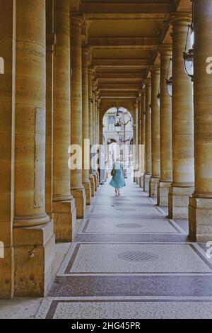 Frau geht durch einen Korridor mit Säulen und antiken Laternen in der Rue de Rivoli, einer berühmten und historischen Straße in Paris, Frankreich Stockfoto