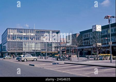 Queen’s Square, Crawley ‘New Town’, West Sussex, England, Großbritannien und sein legendärer Bandstand und Uhrturm, fotografiert 1966. Der Queensway Store (links) war ein Kaufhaus, das 1959 eröffnet wurde. Es ist jetzt die Heimat von Decathlon, einem Sportgeschäft. Die Erweiterung der wichtigsten Einkaufsmöglichkeiten war für Crawleys Expansion unerlässlich. Nach dem Zweiten Weltkrieg wurden viele Menschen und Arbeitsplätze in die neuen Städte im Südosten Englands verlegt, um diejenigen in Londons armen oder bombardierten Wohnungen zu verlagern, und Crawley war das einzige von ihnen – ein altes Foto aus dem Jahr 1960s. Stockfoto