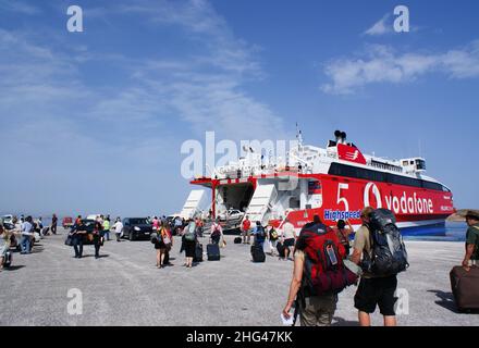 Paros Island - Griechenland - Mai 13 2010 : geschäftiger griechischer Hafen von Parikia. Reisende steigen an Bord der Inter Island Fähre, die am Hafen anlegt. Landschaftsbild Stockfoto