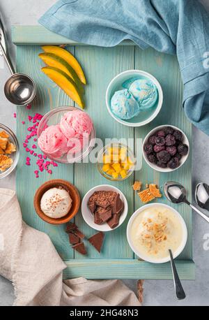 Eis mit verschiedenen Geschmacksrichtungen mit Beeren und Früchten auf einer blauen Tafel. Draufsicht, vertikal. Stockfoto