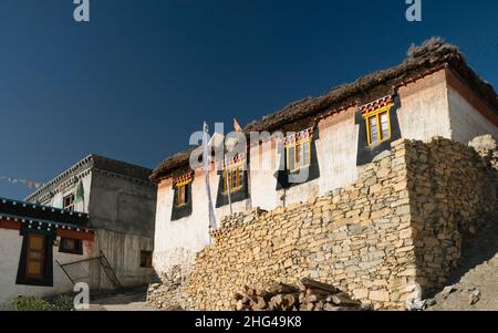 Traditionelle Dorfhäuser mit Flachdächern und buddhistischen Gebetsfahnen unter blauem Himmel im Dorf Kibber, Himachal Pradesh, Indien. Stockfoto