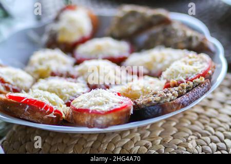 Nahaufnahme eines frischen Sandwiches auf dem Teller mit geriebenem Käse und Tomaten. Stockfoto