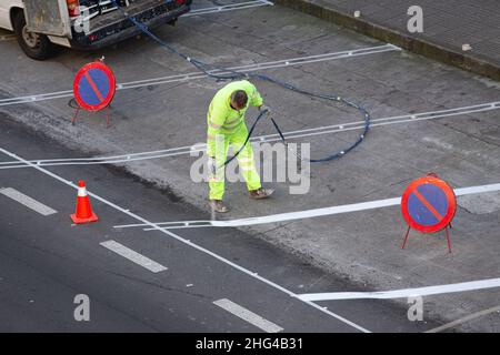 Galicia, Spanien; 18. januar 2022: Straßenmaler malt mit einer Spritzpistole Linien auf Asphalt Stockfoto