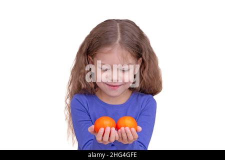 Lächelndes und glückliches Kind Kind hält Tandarinen in den Händen, isoliert auf weißem Hintergrund Blick auf Früchte Taille bis kaukasischen kleinen Mädchen von 5 Jahren in b Stockfoto